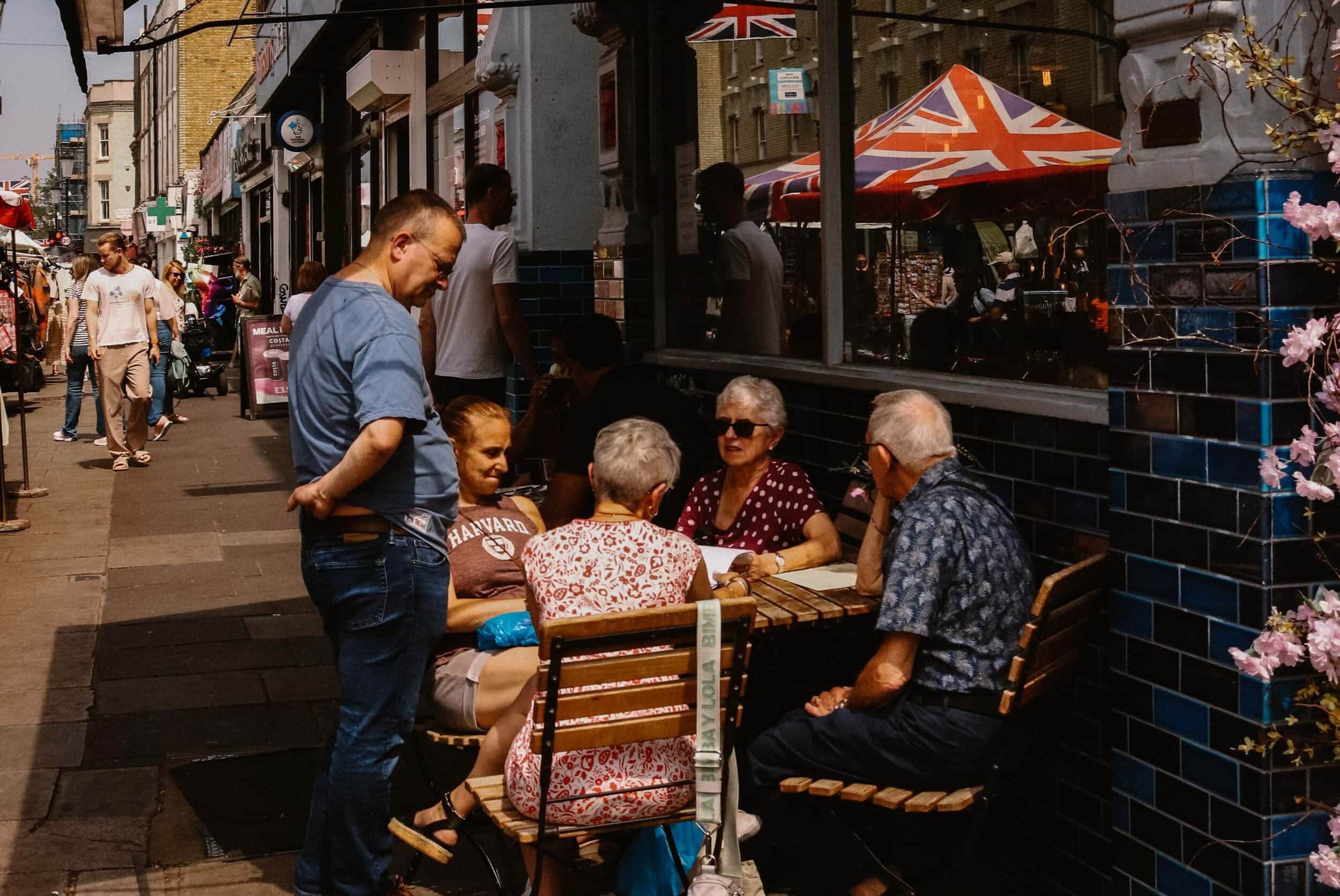 People enjoying outdoor dining at a cafe with Union Jack umbrellas in London.