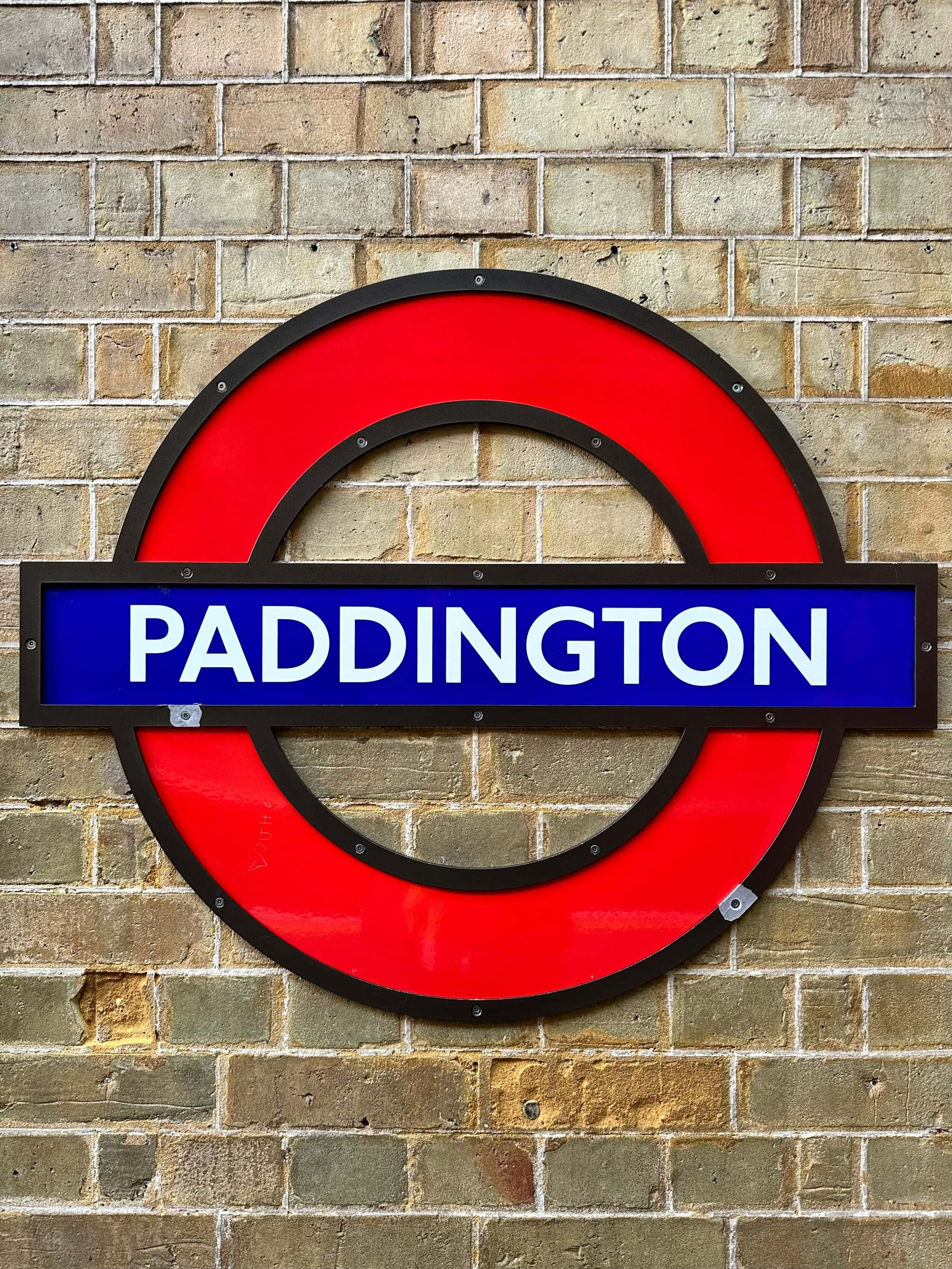 London Underground Paddington station sign on brick wall.