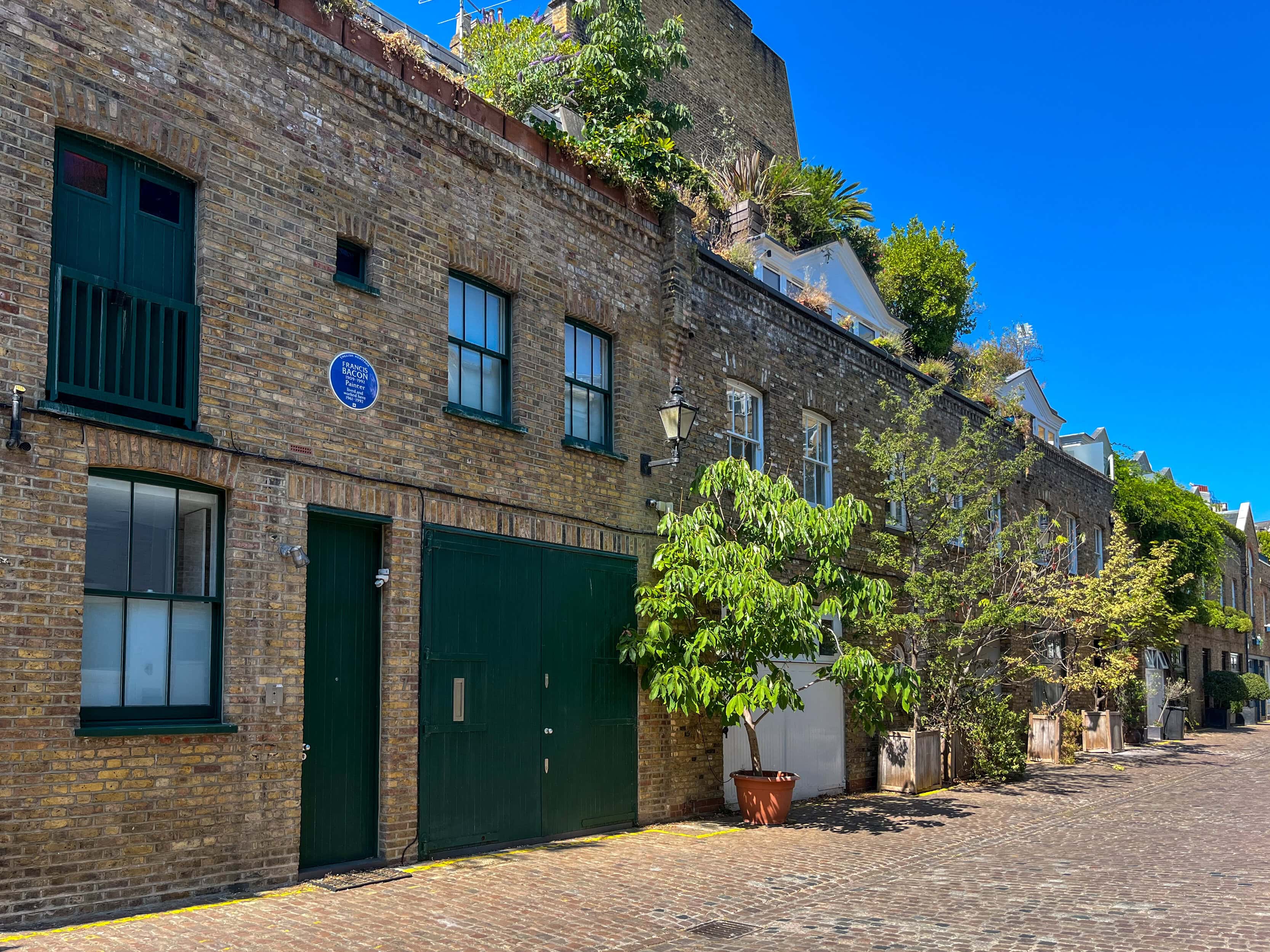 Historic London mews street with blue plaques and traditional brick buildings.